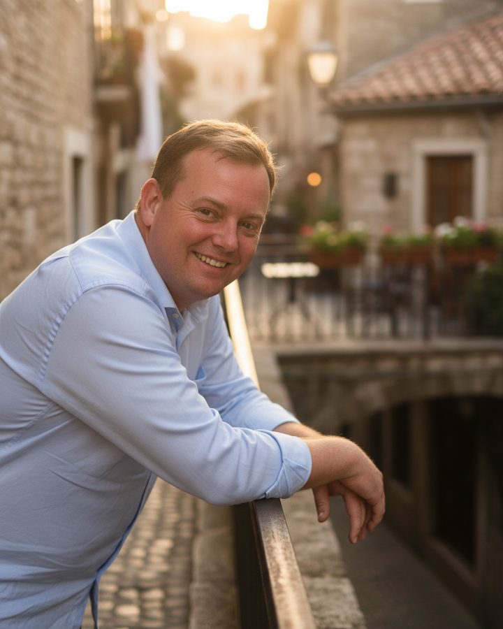 Jesper smiling on a balcony in an old town